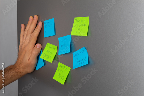 Reminders taped to fridge door and hand holding to read them photo