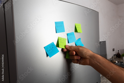 Reminders taped to fridge door and hand holding to read them photo