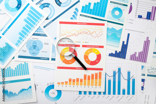 Business chart and magnifier on the desktop. Desktop of a businessman. The concept of analysis and determination of key information in business.