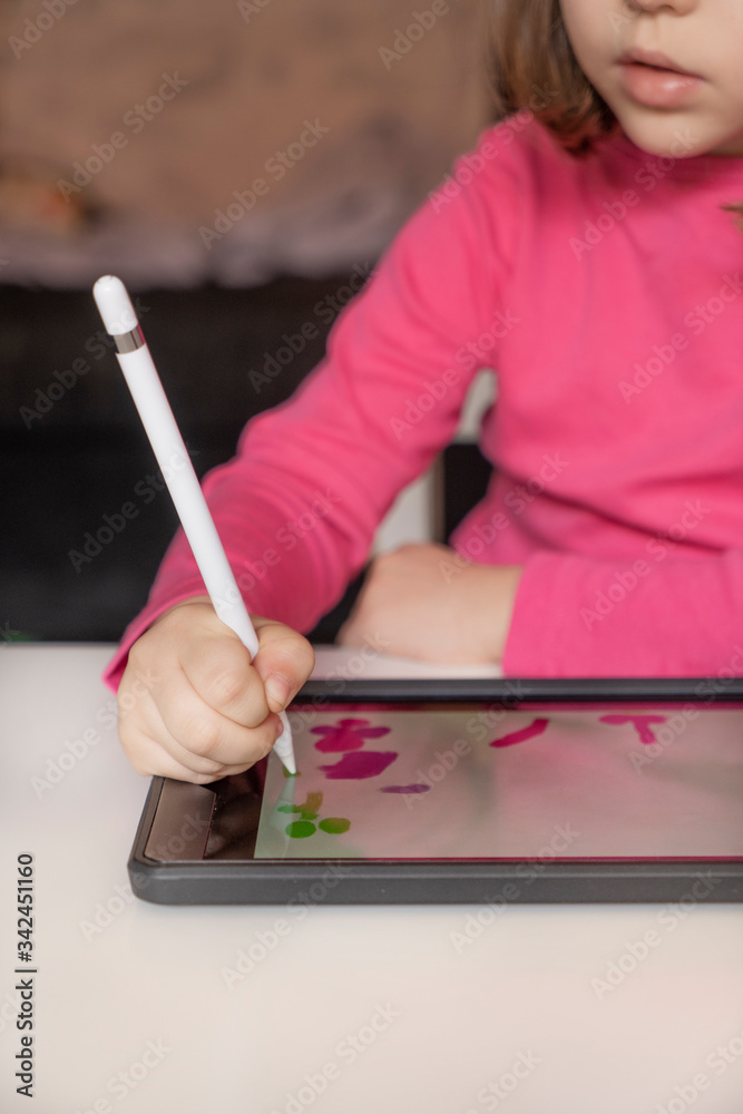 Caucasian girl drawing with the tablet with white pencil. Creating figures with your imagination and learning at home. vertical shot. Caucasian girl drawing with the tablet with white pencil. Creating figures with your imagination and learning at home. vertical shot.