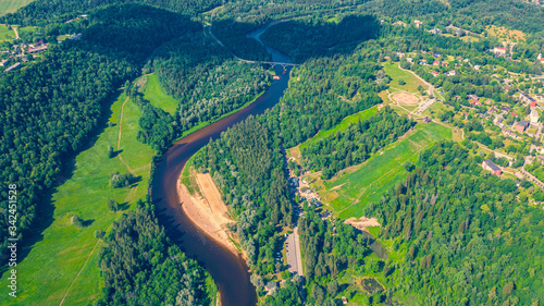 Fototapeta Naklejka Na Ścianę i Meble -  Panoramic aerial view photo from flying drone on beautiful forests of Sigulda, the meadows, and the flowing river Gauja. Sigulda, Latvia in summer (series)