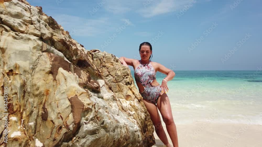 Girl on the beach of an uninhabited island next to a large stone Girl on the beach of an uninhabited island next to a large stone