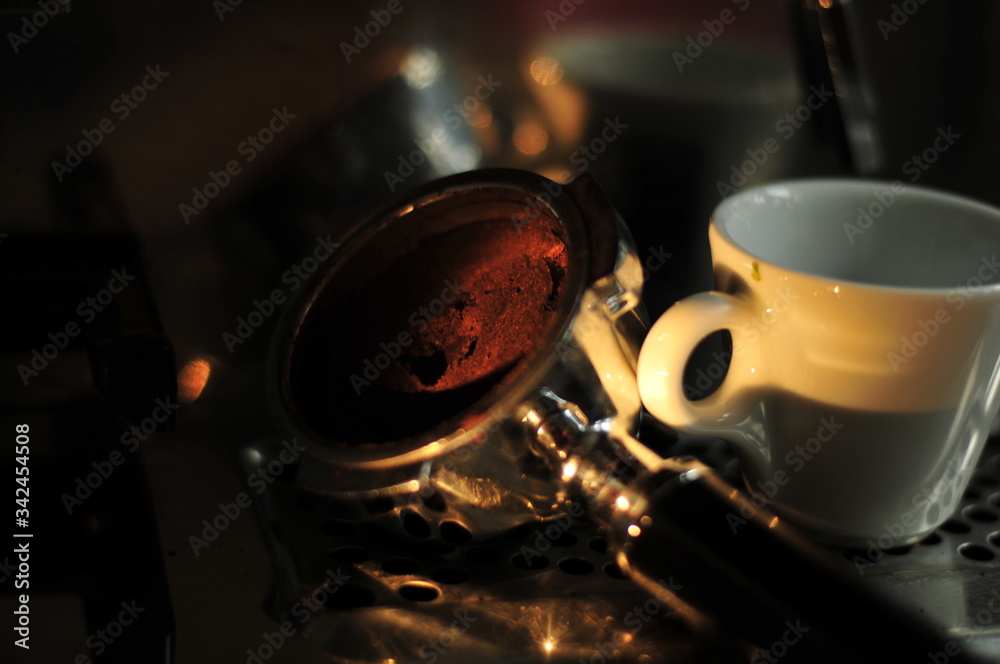 darkened picture with stylish light on screen carrier coffee machine and espresso cup