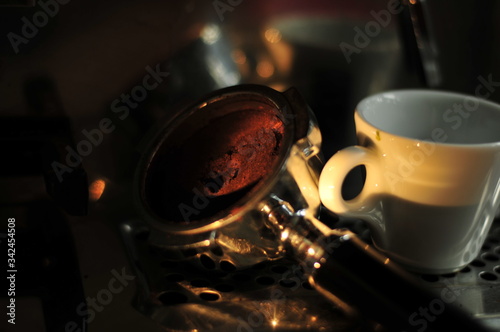 darkened picture with stylish light on screen carrier coffee machine and espresso cup