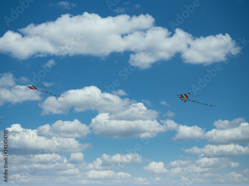 Kite flying against blue sky with clouds.