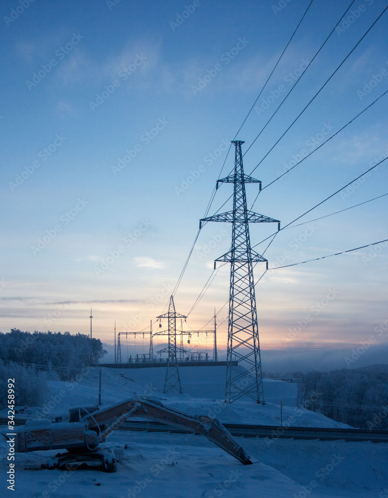 high voltage power line on a winter background of the setting sun