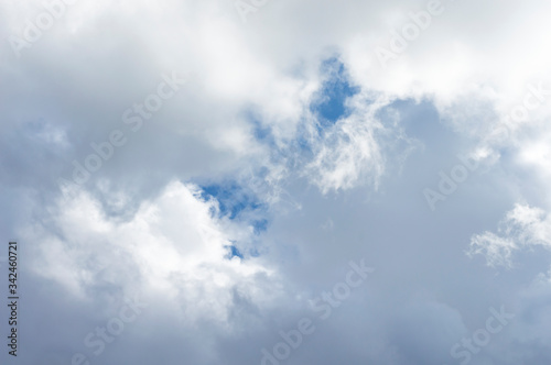 Thick clouds in the blue sky. Background photo of clouds where the sun shines through. © zyryanova