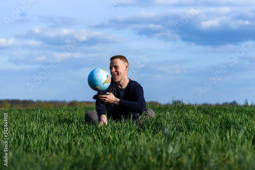  man sits in green field and licks earth globe