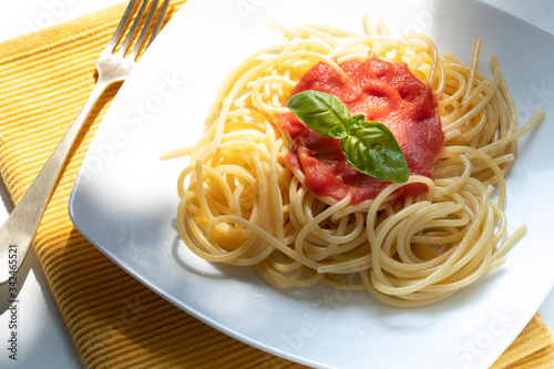фотографія dish with spaghetti and tomato sauce on the white table
