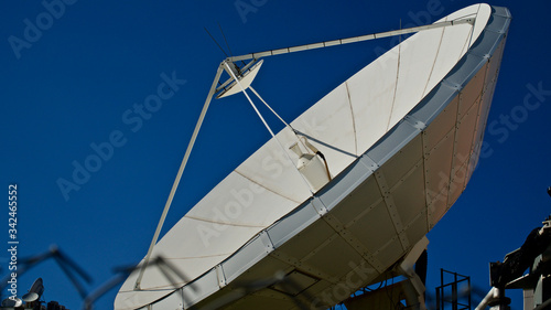 Large satellite dish. TV and radio broadcasting antenna. In front of blue sky.