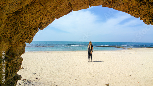 Caucasian blonde woman standing on beach by Roman aqueduct, Caesarea, Israel