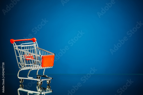 empty shopping cart, blue copy-space background