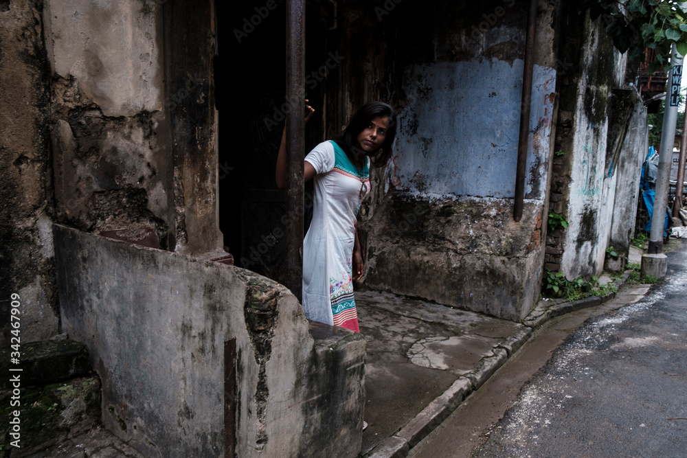 Portrait of a beautiful brunette dark skinned Indian Bengali woman in white ethnic dress standing in a narrow lane. Indian lifestyle