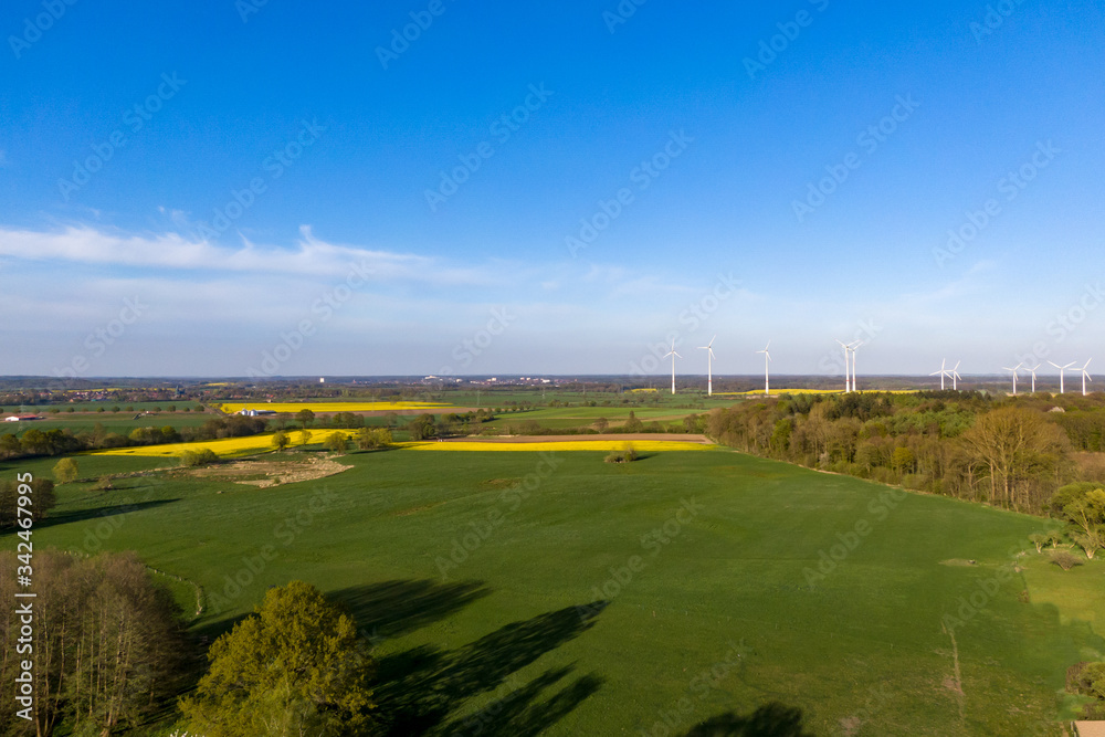 Fototapeta premium Vogelperspektive Blick über Wiesen, Felder und Wälder auf Windräder