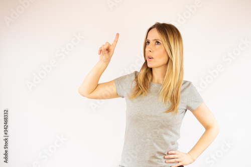 Young woman in grey shirt pointing with finger up