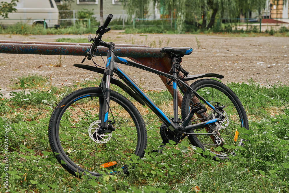 the bike is locked near an iron pillar in the yard.