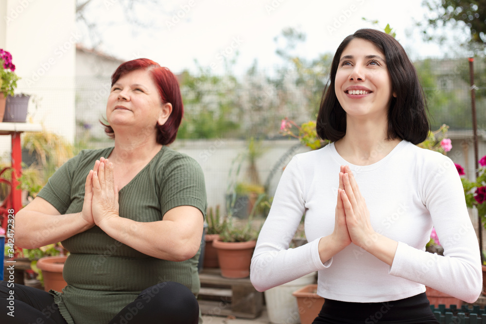 the mature woman and her young daughter do yoga in the garden. The mother and daughter, who are in quarantine for the coronavirus, are spending time at home. the mature woman and her young daughter do yoga in the garden. The mother and daughter, who are in quarantine for the coronavirus, are spending time at home.