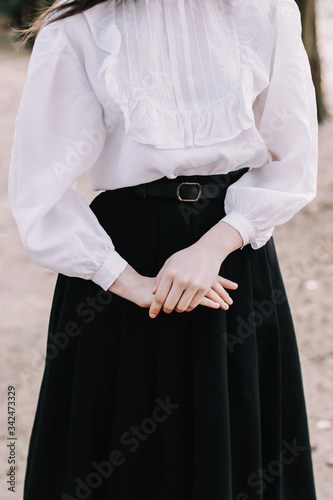 Student or college girl in uniform. Hands of the girl close-up. Girl wearing black skirt and white blouse