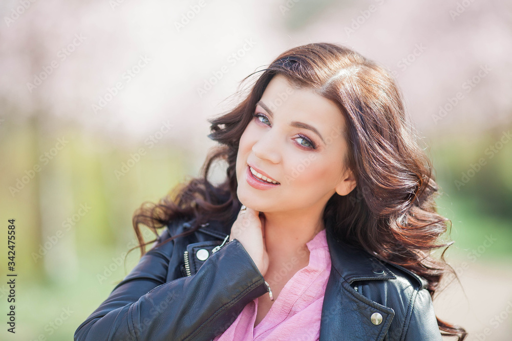 A beautiful young woman is walking in a flowered garden. Portrait of a dark-haired young woman. Cherry blossoms. Spring. A beautiful young woman is walking in a flowered garden. Portrait of a dark-haired young woman. Cherry blossoms. Spring.