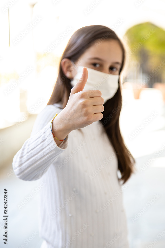 Bambina con mascherina fa segno positivo con la mano, virus quarantena Bambina con mascherina fa segno positivo con la mano, virus quarantena