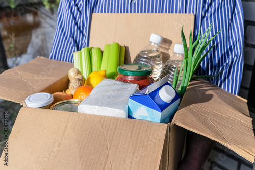 A man holds a box with groceries. Home delivery concept.