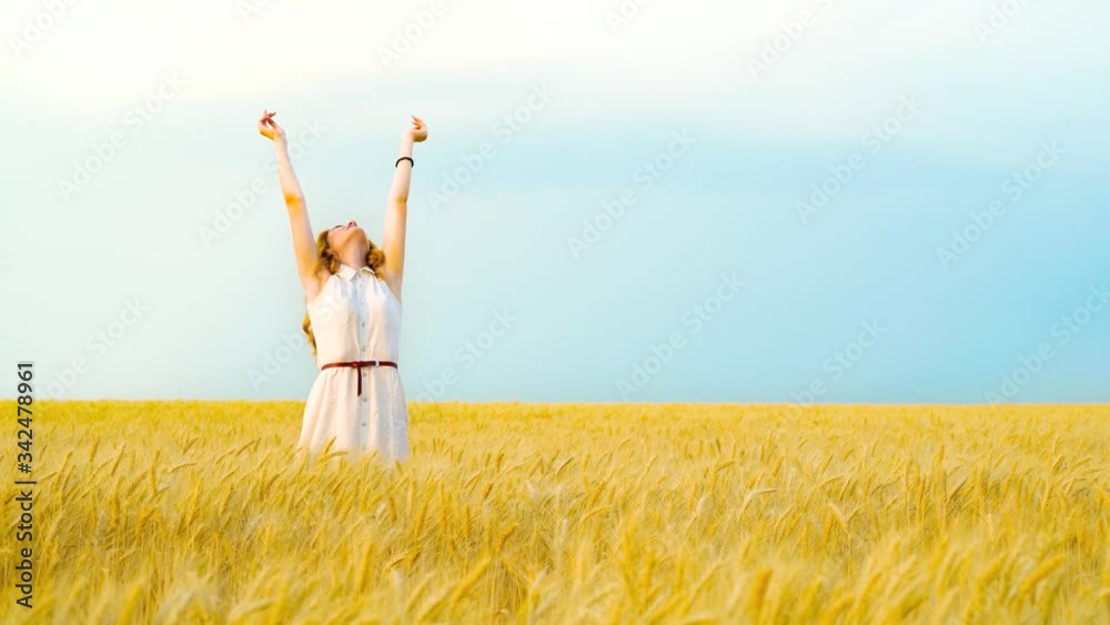 Beautiful girl raising hands in wheat field at harvest season Beautiful girl raising hands in wheat field at harvest season