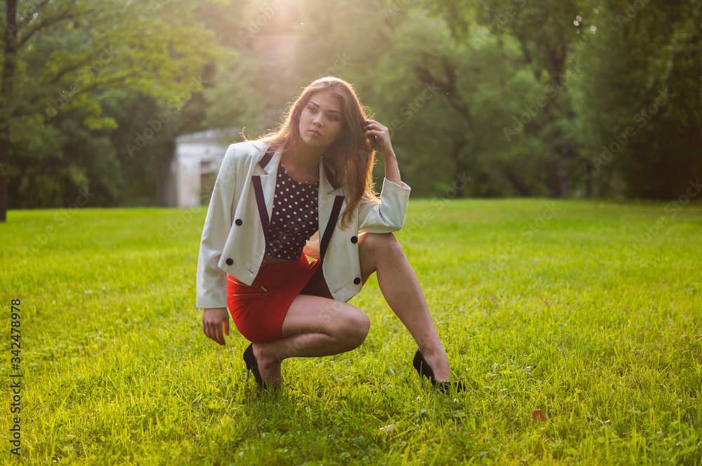 Sexy woman in a red skirt posing outdoors in the park.A bitchy girl