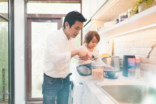 Daddy and son busy in the kitchen, fatherhood learning to be babysitter and teaching his kid for kitchen stuff while mother not in the house, Single dad with son in the house during covid-19 crisis.
