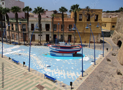 Square in the city of Melilla with fishing boat on the tiled blue floor. Spain.