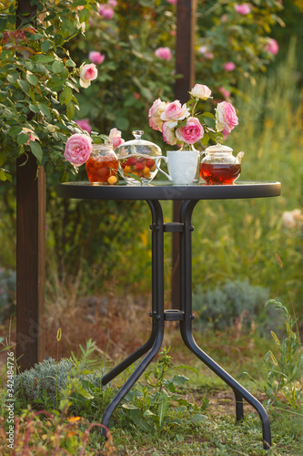 Jam in glass jar. Romantic dinner in the garden under a rose bush Pierre de Ronsard. Summer time