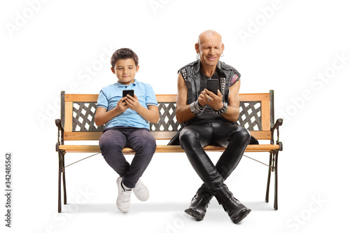 Boy and a punk sitting on a bench and typing on mobile phones