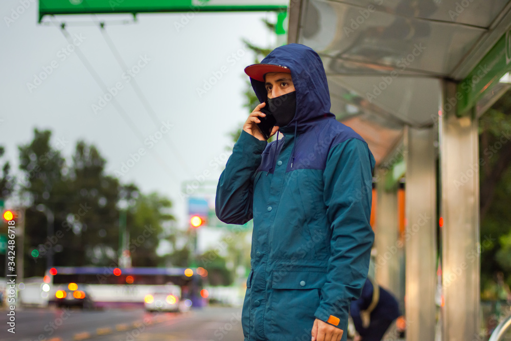 Young man wears a face mask and talks on the phone on the street