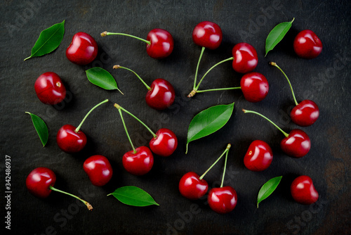 Cherries background. Cherries on black top view. Cherry background. Sour cherry with leaves on black background.
