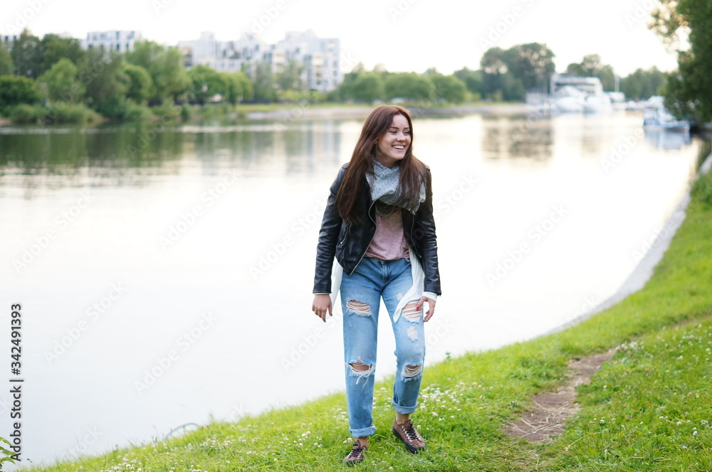 A cute and cute teenager girl is fashionably dressed and she walks in the park with a white backpack. The modern style of society. Freedom of movement. Walk in the park A cute and cute teenager girl is fashionably dressed and she walks in the park with a white backpack. The modern style of society. Freedom of movement. Walk in the park
