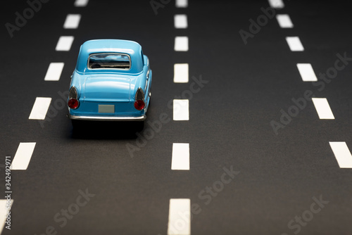 Rear view of a blue toy car on an asphalt road