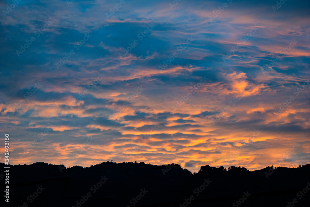 Dramatic clouds in the sky at sunrise in rural Guatemala, silhouette of mountains, forest area.

