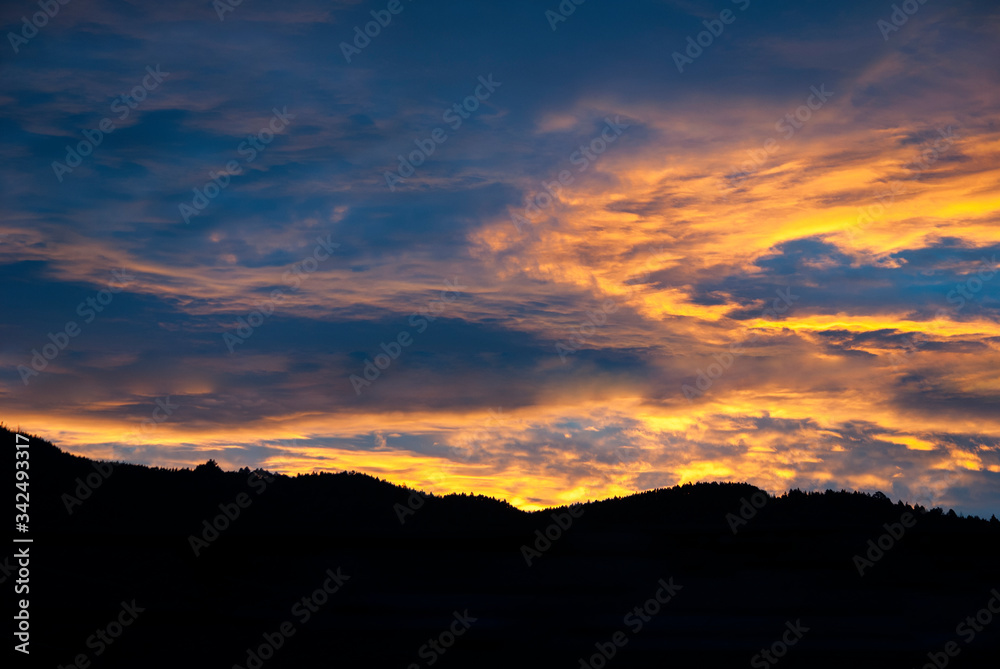 Dramatic clouds in the sky at sunrise in rural Guatemala, silhouette of mountains, forest area.

