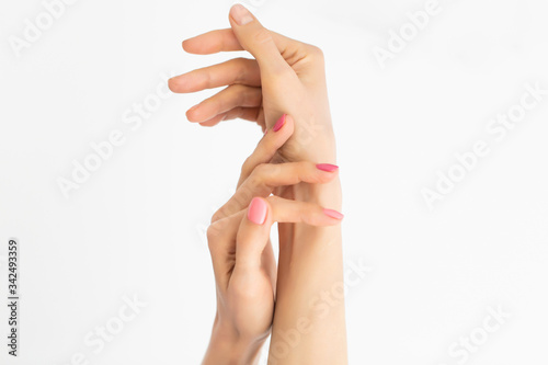 Close-up of women's hands, one with a manicure, and the other without. Hands on a white background