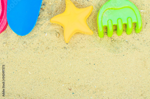 Toys for the sandbox. Children's toys in the sand. Shovel, rake and asterisk. Place for your text.