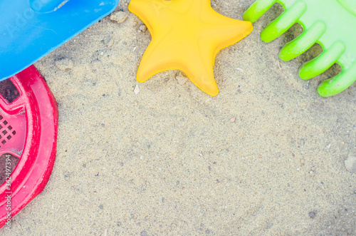 Toys for the sandbox. Children's toys in the sand. Shovel, rake and asterisk. Place for your text.