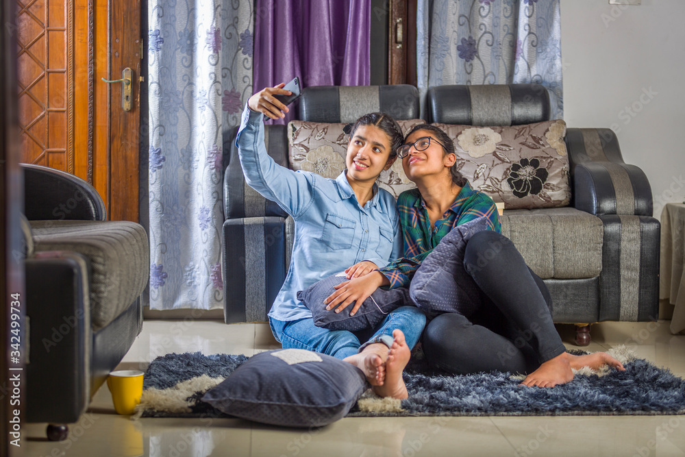 Obraz premium two girls sitting at home taking selfie and having fun