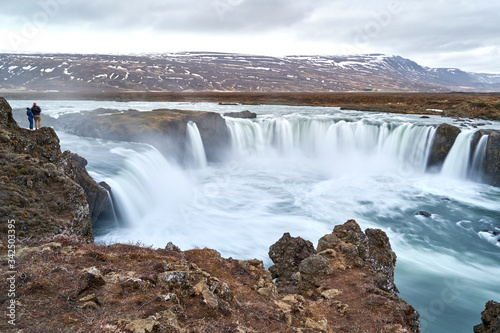 Two People Standing Above Godafoss Waterfall at Iceland