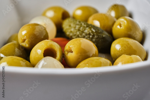 Macro olives with pickles, mini onions, carrot in a white bowl. Home or bar appetizer.