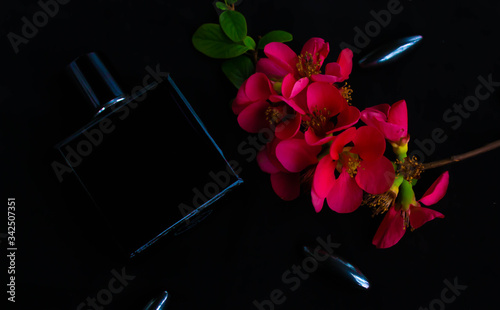 Black parfume bottle on the black background with flowers photo