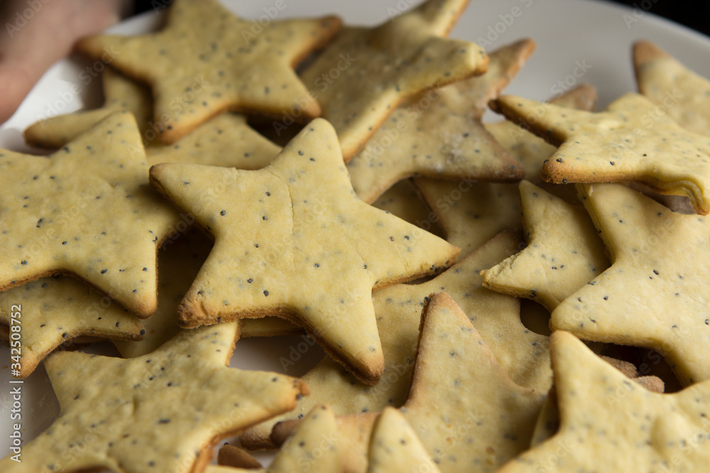 on a plate are many home-made sandy gluten-free yellow poppy cookies in the form of stars on a plate are many home-made sandy gluten-free yellow poppy cookies in the form of stars