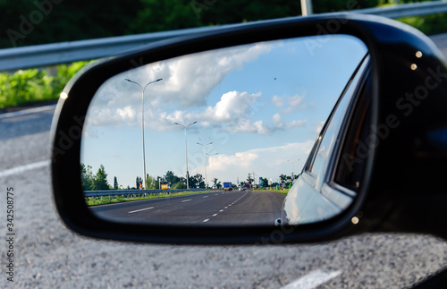 reflection of the road in the car mirror, with the sky and clouds, warm summer evening