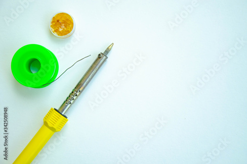 Soldering iron, tin, rosin on a white background. Soldering iron in male hands. Macro. Repair of electrical equipment, radio engineering. Solder wires, contacts.  Copy Space