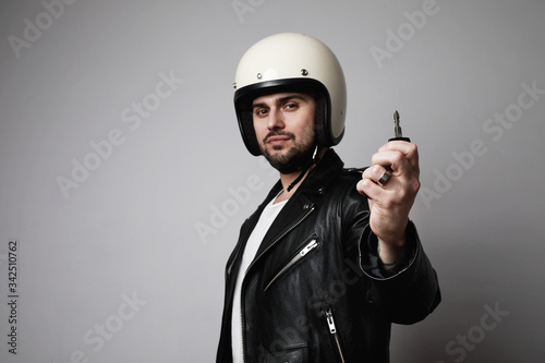 Handsome bearded man over white background with serious face wearing white helmet showing a key for his vehicle.