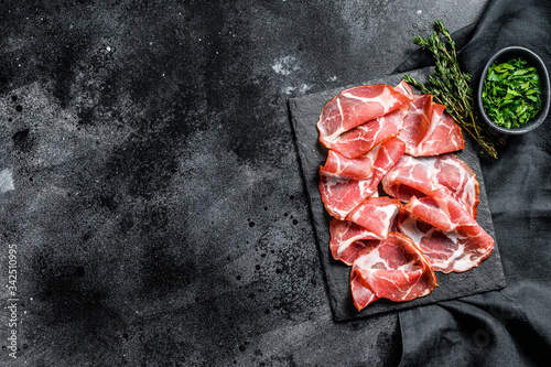 Italian rolled bacon Pancetta Piacentina. Pork meat. Black background. Top view. Copy space