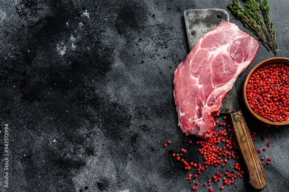 Raw pork marbled steak on a meat cleaver. Black background. Top view. Copy space